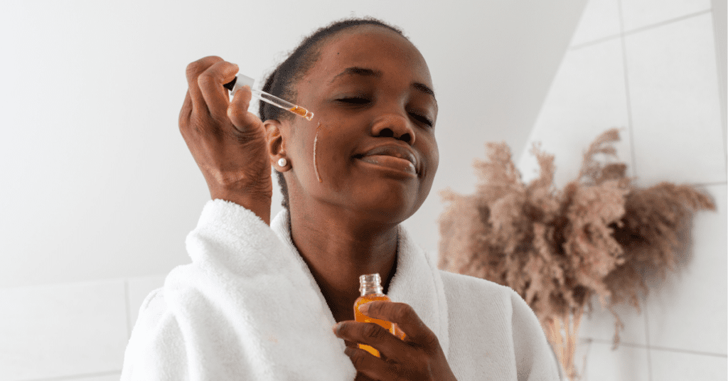 Black woman with prurigo nodularis applying tea tree oil to her face